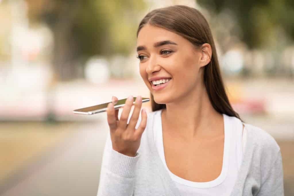 Woman using digital voice assistant on cellphone outdoor